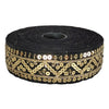 Roll of black ribbon with gold sequin detailing on a white background