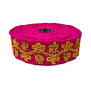 Roll of pink fabric with gold embroidery on a white background