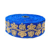 Roll of blue ribbon with gold floral embroidery on a white background