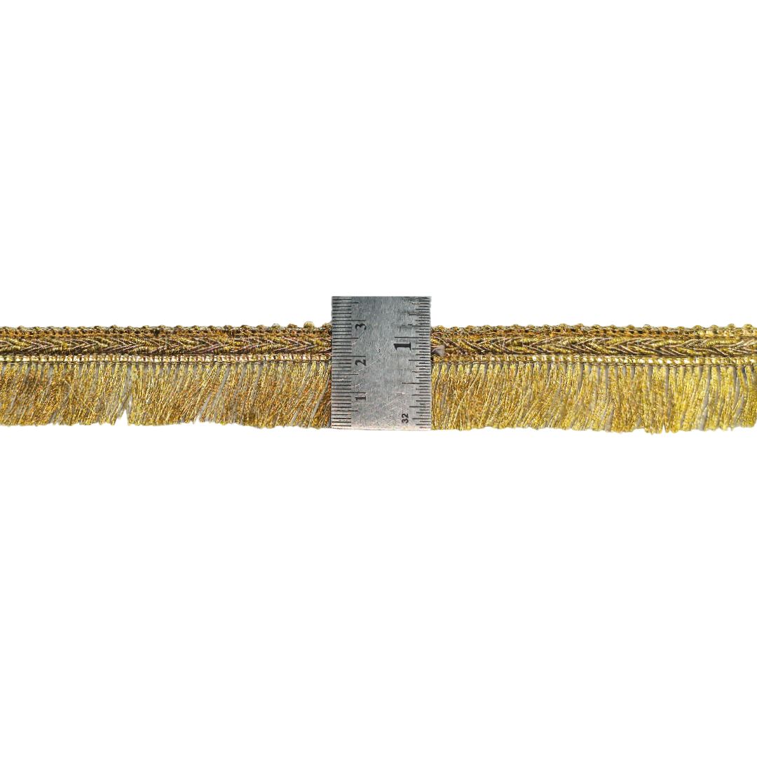 Gold fringe trim with a ruler for scale on a white background
