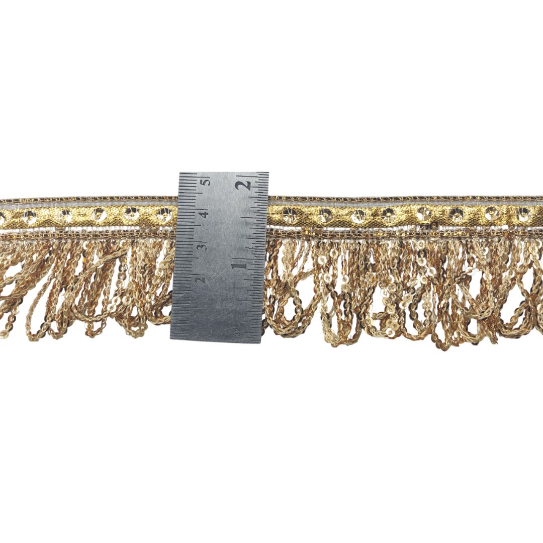 Gold fringe trim with a ruler for scale on a white background