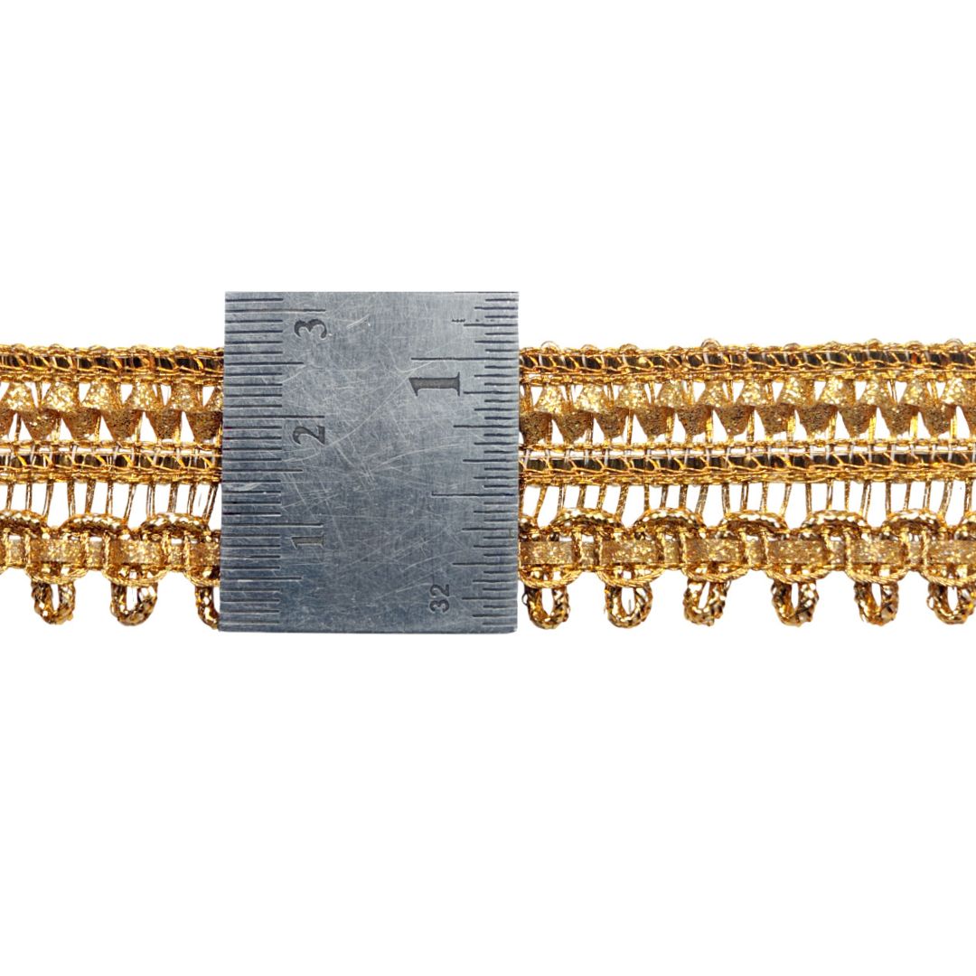 Gold lace trim with a ruler for scale on a white background