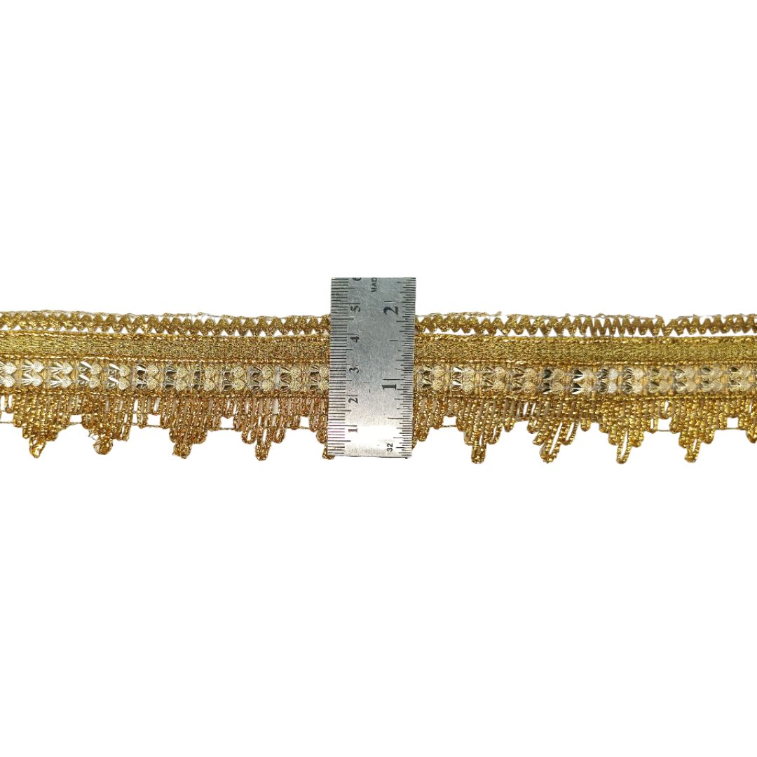 Gold fringe trim with a ruler for scale on a white background