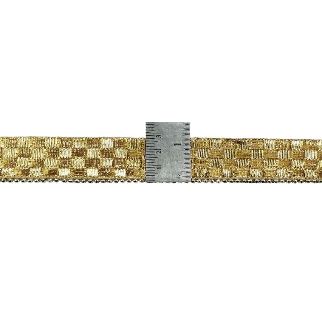Gold woven ribbon with a ruler for measurement on a white background