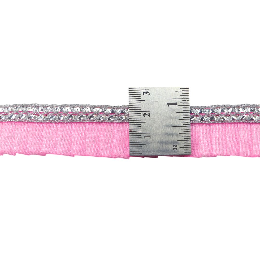 Pink ribbon with a silver border and a ruler for measurement on a white background