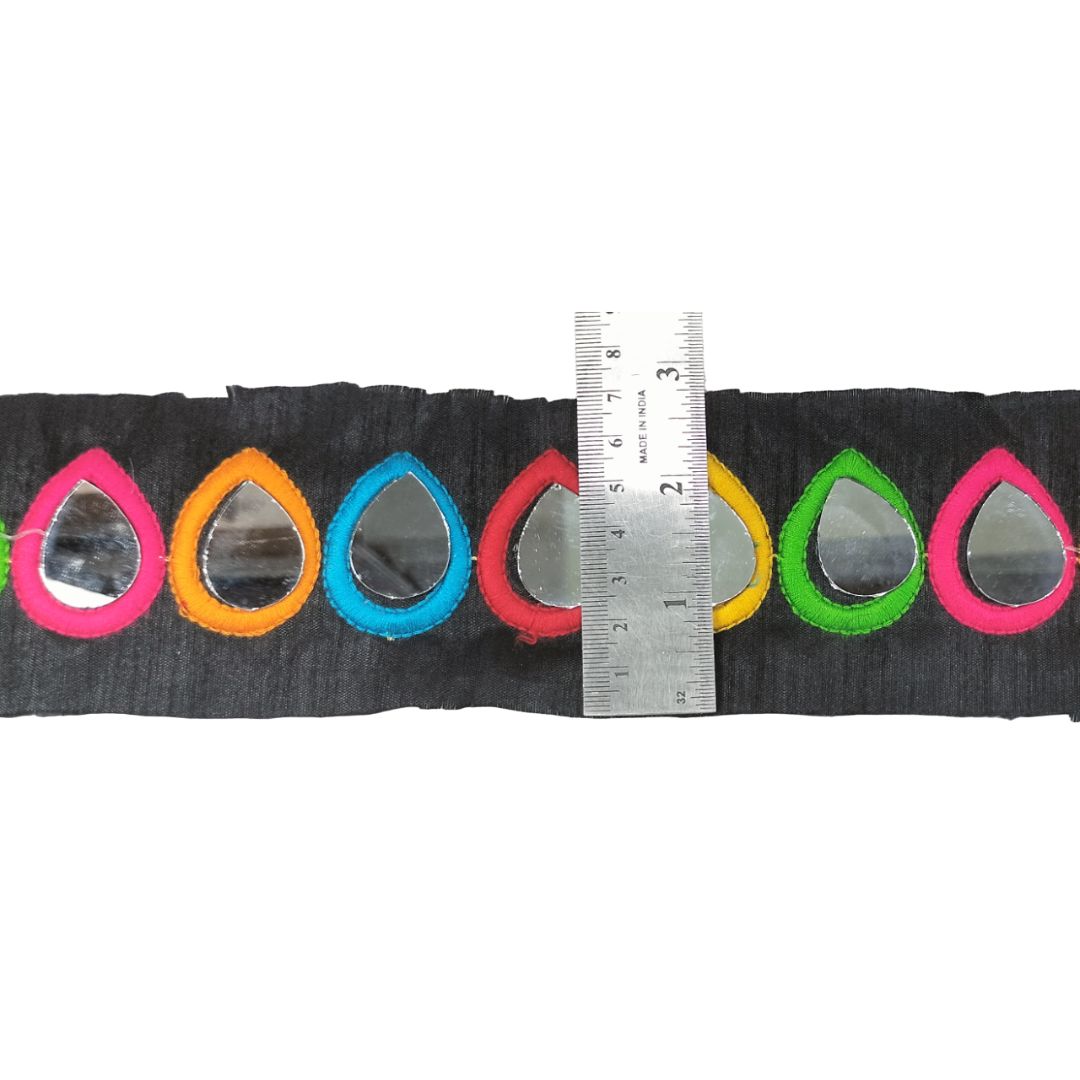 Strip of fabric with colorful mirror teardrop shapes and a ruler for scale on a white background