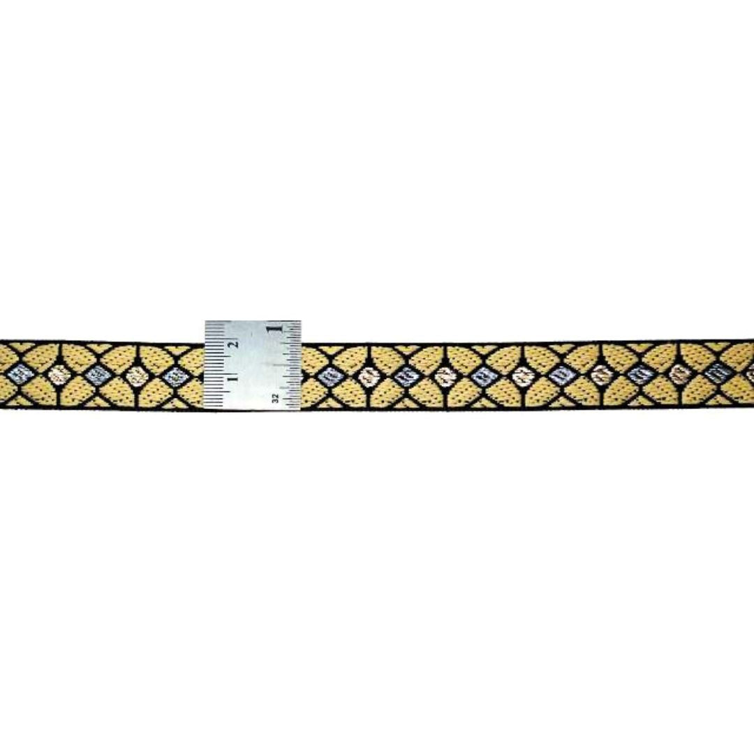 Gold and black patterned belt with a ruler for scale on a white background