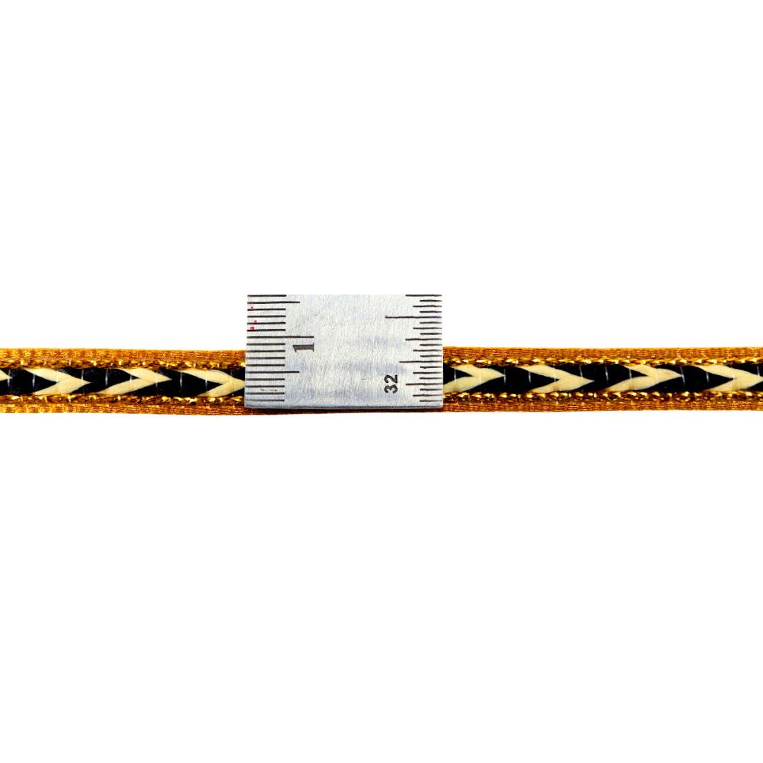 Braided gold and black cord with a ruler for scale on a white background