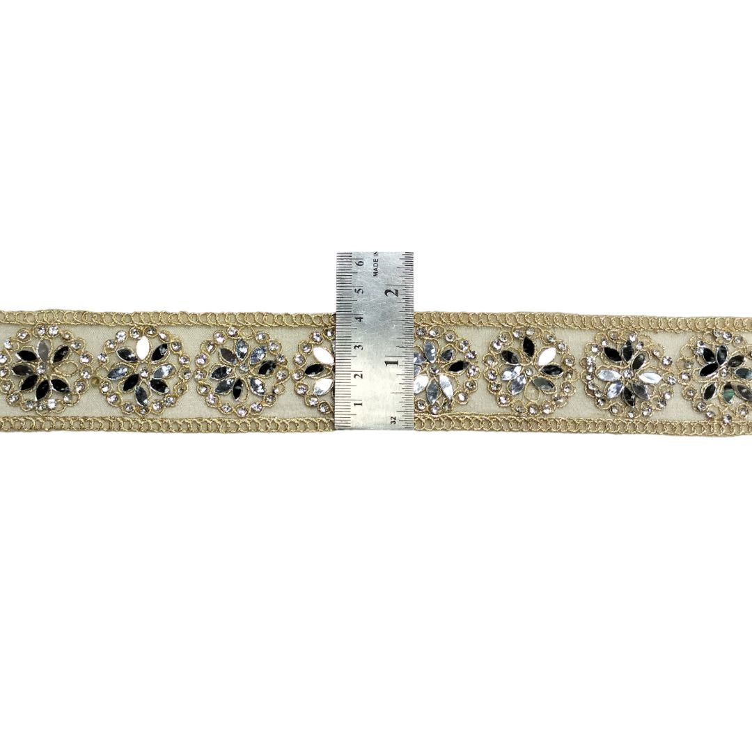 Decorative ribbon with floral patterns and rhinestones next to a ruler on a white background