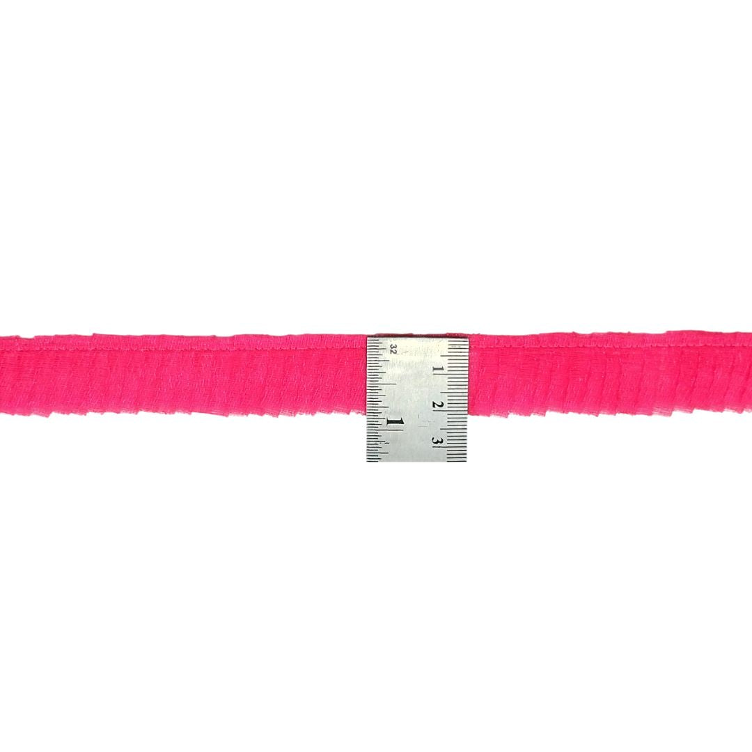 Neon pink ribbon with a ruler for scale on a white background