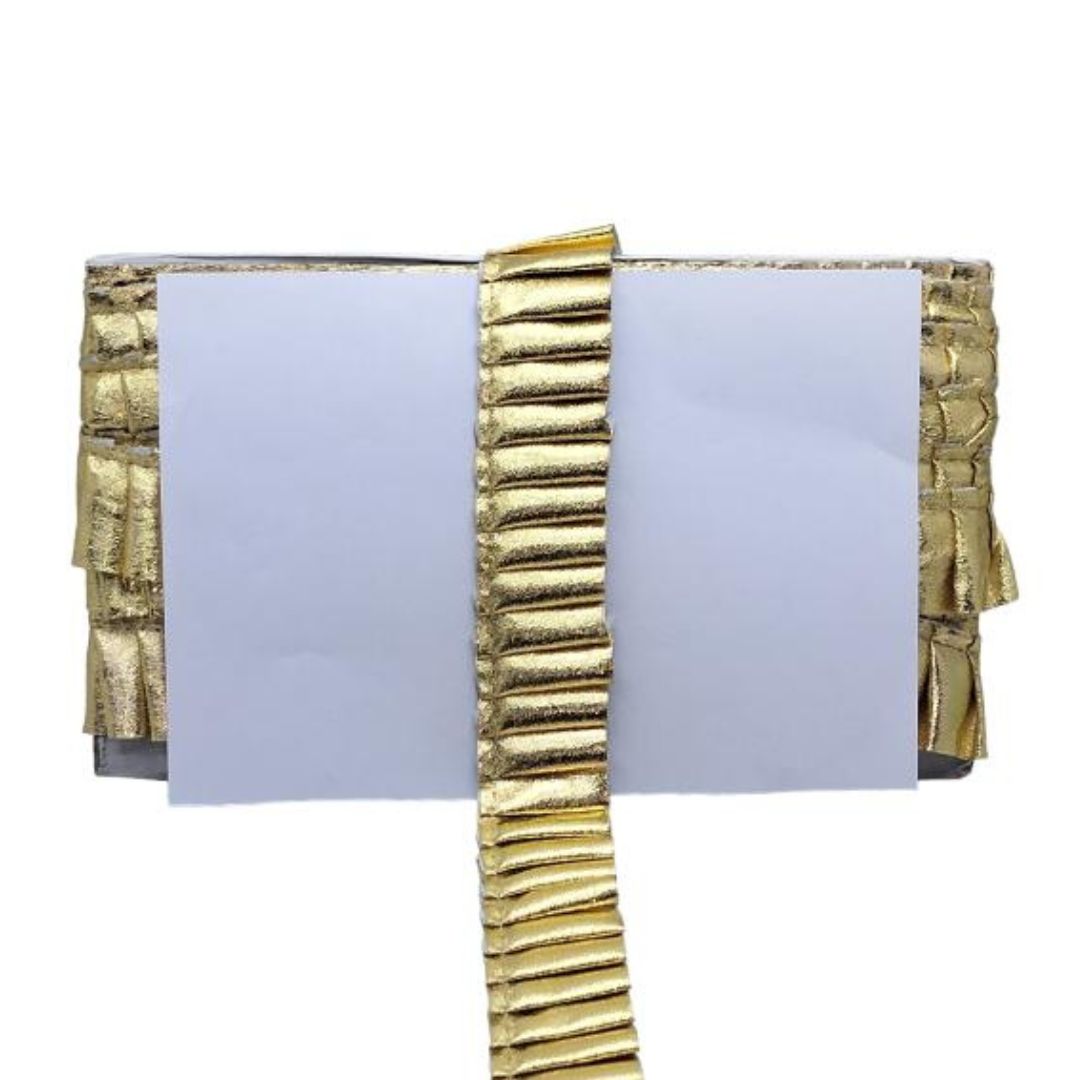 Gold decorative item with ribbed texture on a white background