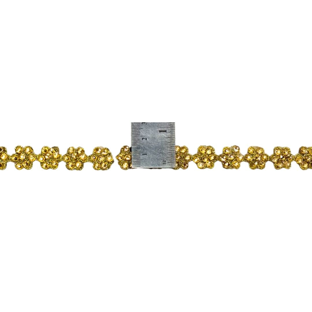 Gold floral chain with a ruler for scale on a white background