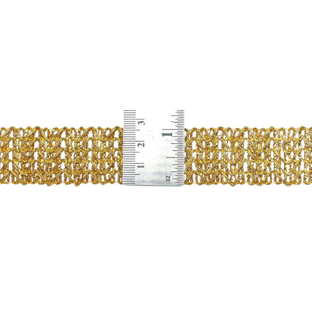 Gold bracelet with a ruler for scale on a white background