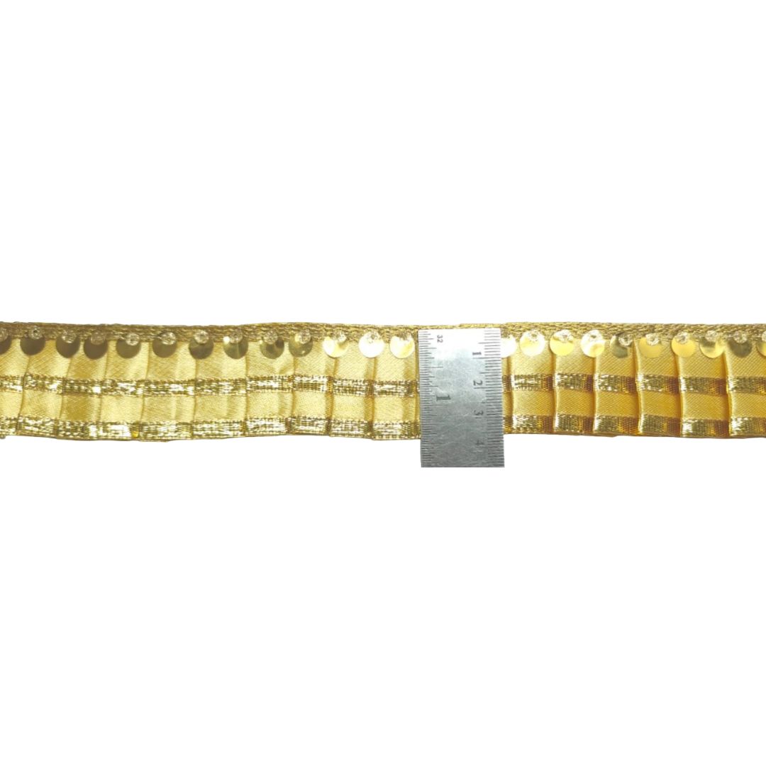 Gold sequin trim with a ruler for scale on a white background