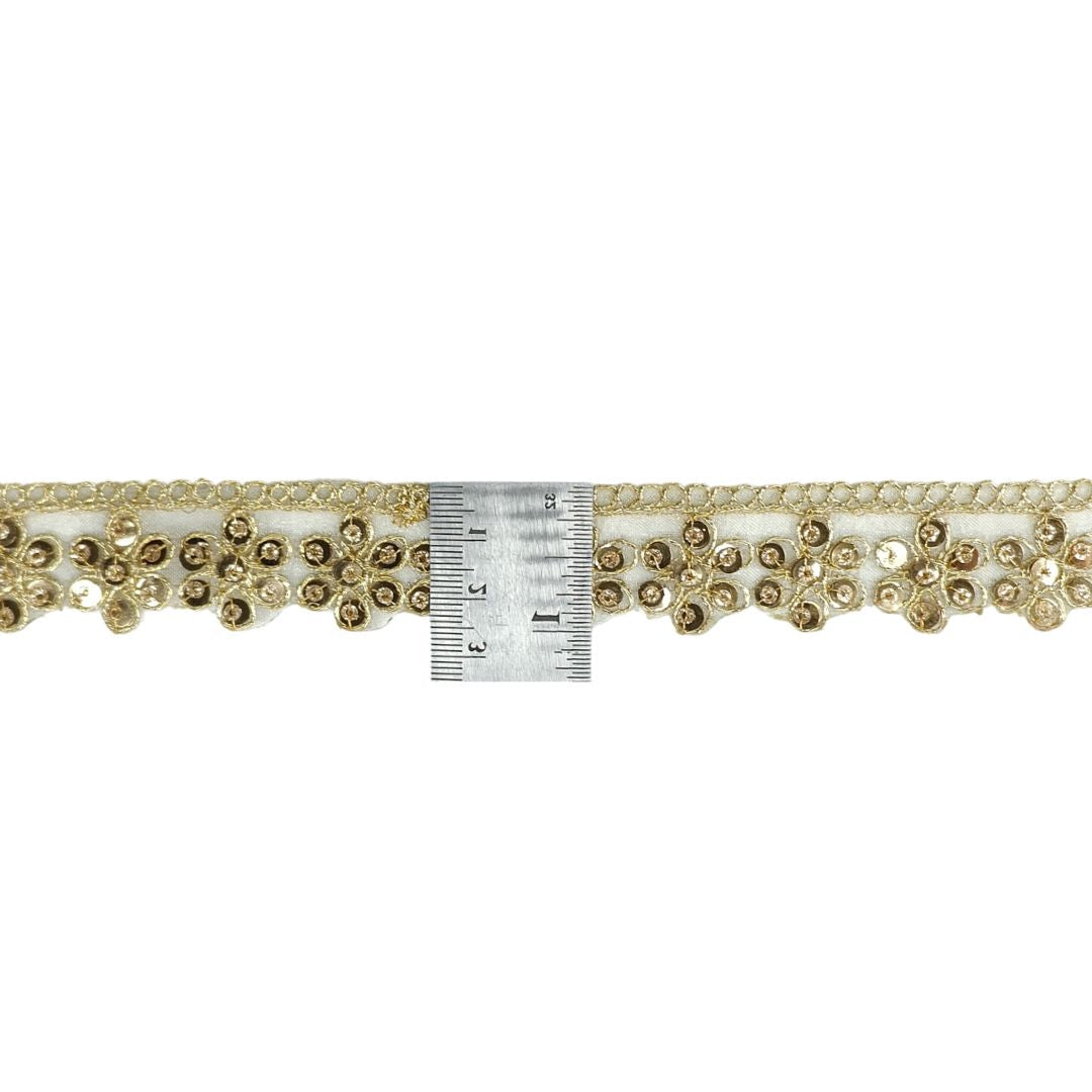 Decorative trim with gold embellishments and a ruler for scale on a white background