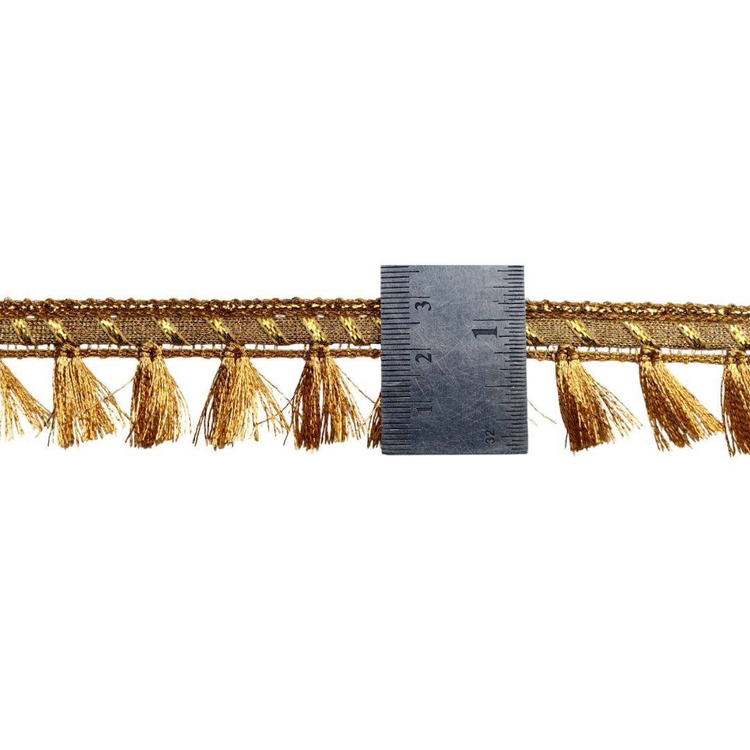 Gold fringe trim with a ruler for scale on a white background