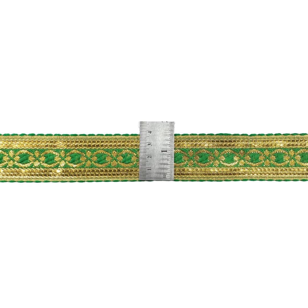 Green ribbon with gold pattern and a ruler for scale on a white background