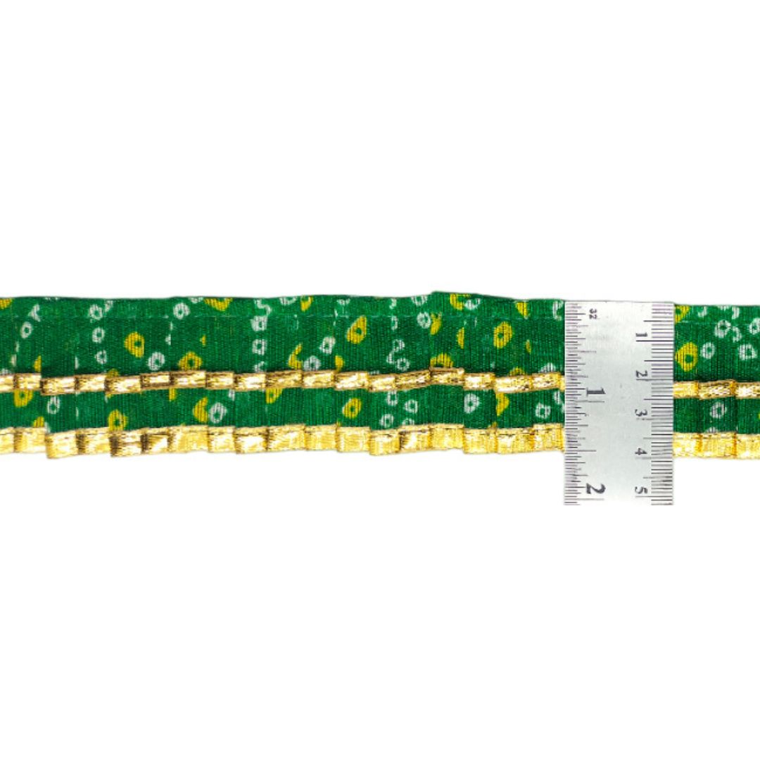 Green ribbon with gold pattern and a ruler for scale on a white background