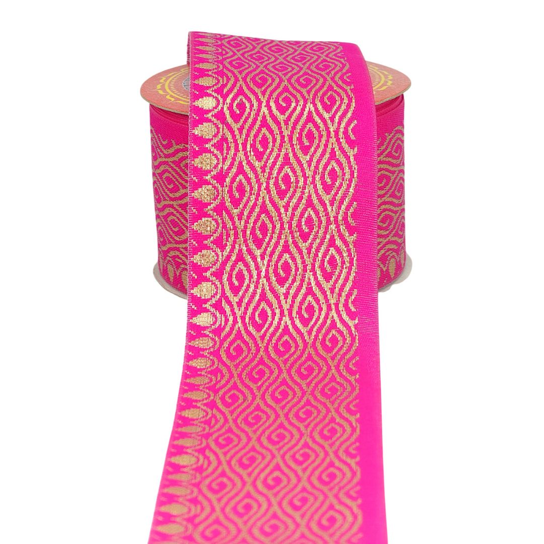 Roll of pink fabric with gold geometric pattern on a white background