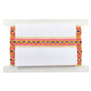 Decorative ribbon with pink and gold patterns on a white card, placed on a white surface.