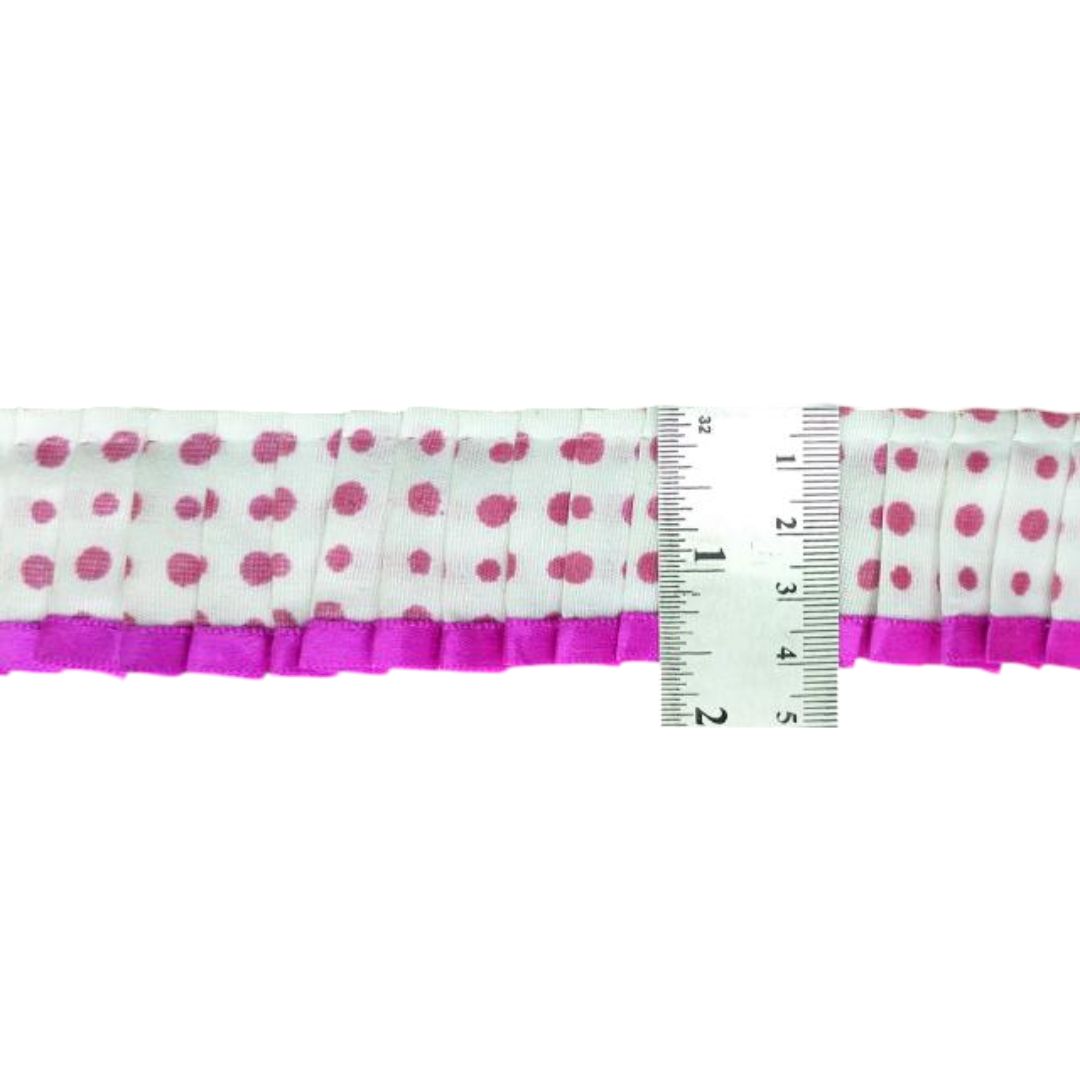 Polka dot ribbon with pink border and a ruler for scale on a white background