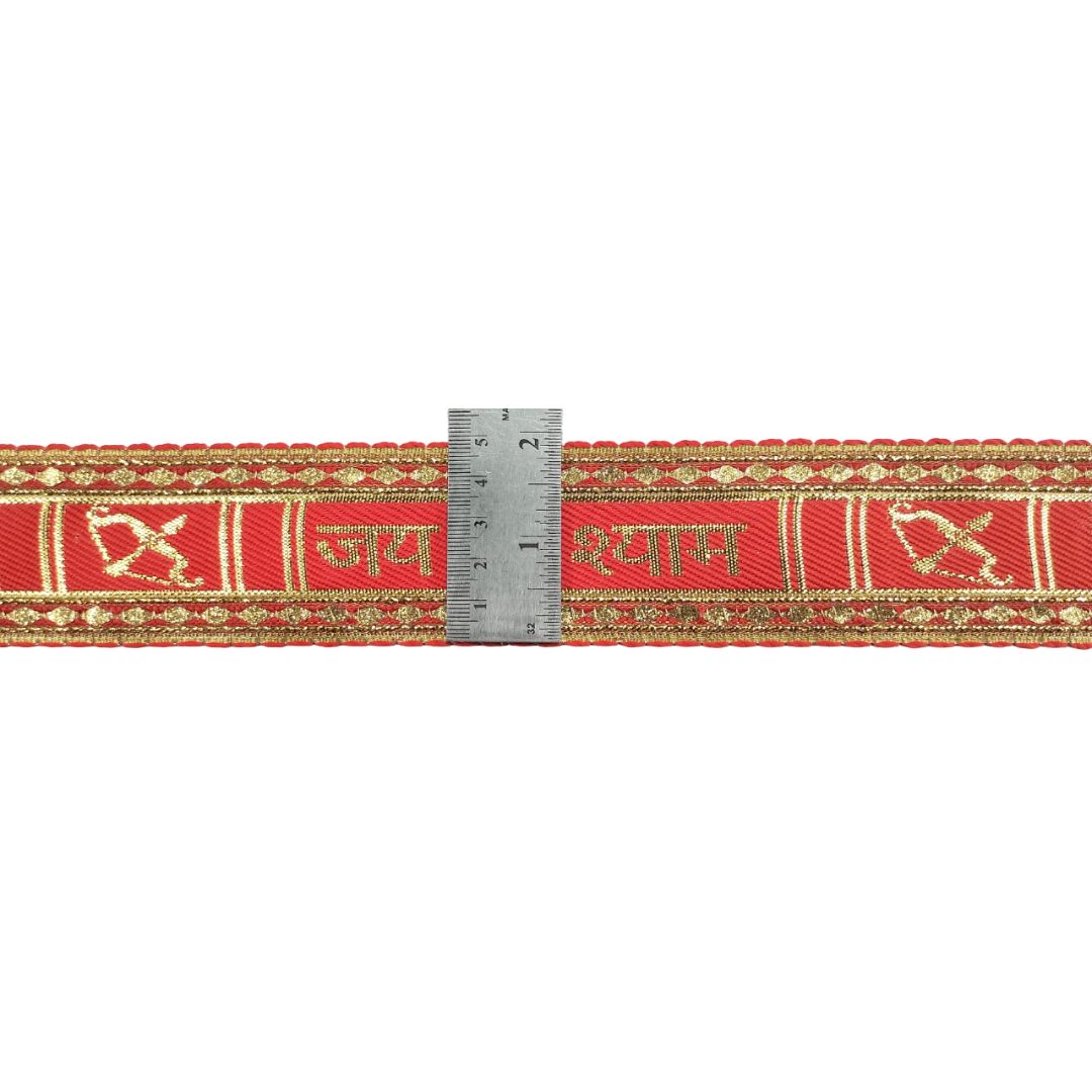 Red fabric strip with gold patterns and a ruler for scale on a white background