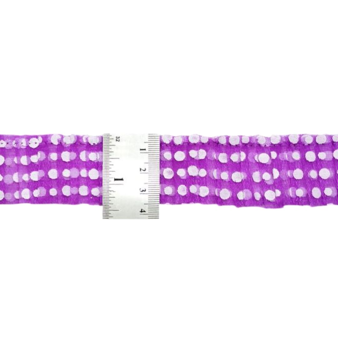 Purple ribbon with white polka dots and a ruler for scale on a white background