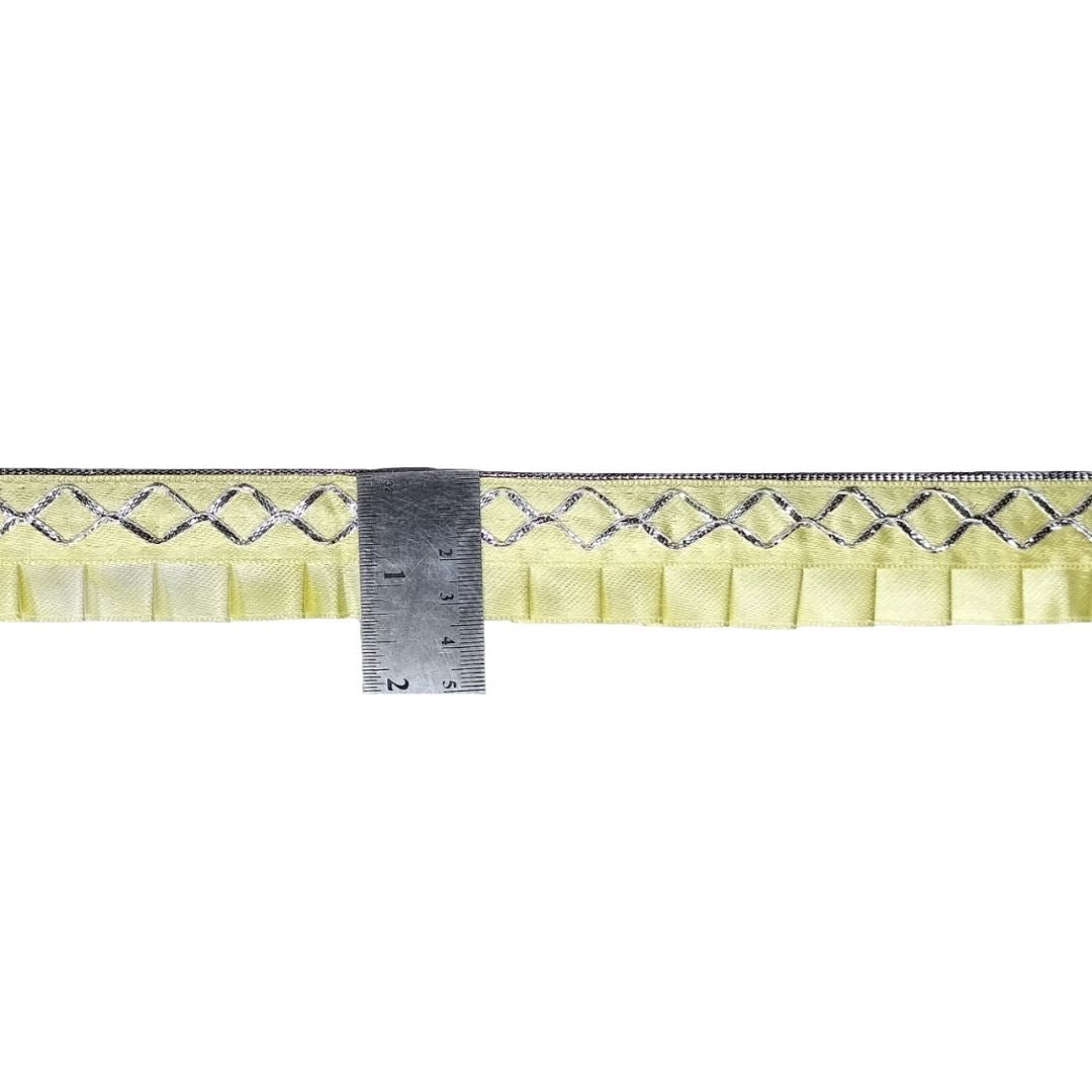 Strip of yellow fabric with a diamond pattern and a ruler for scale on a white background