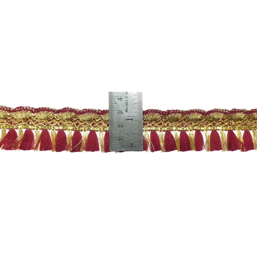 Red and gold fringe fabric with a ruler for scale on a white background