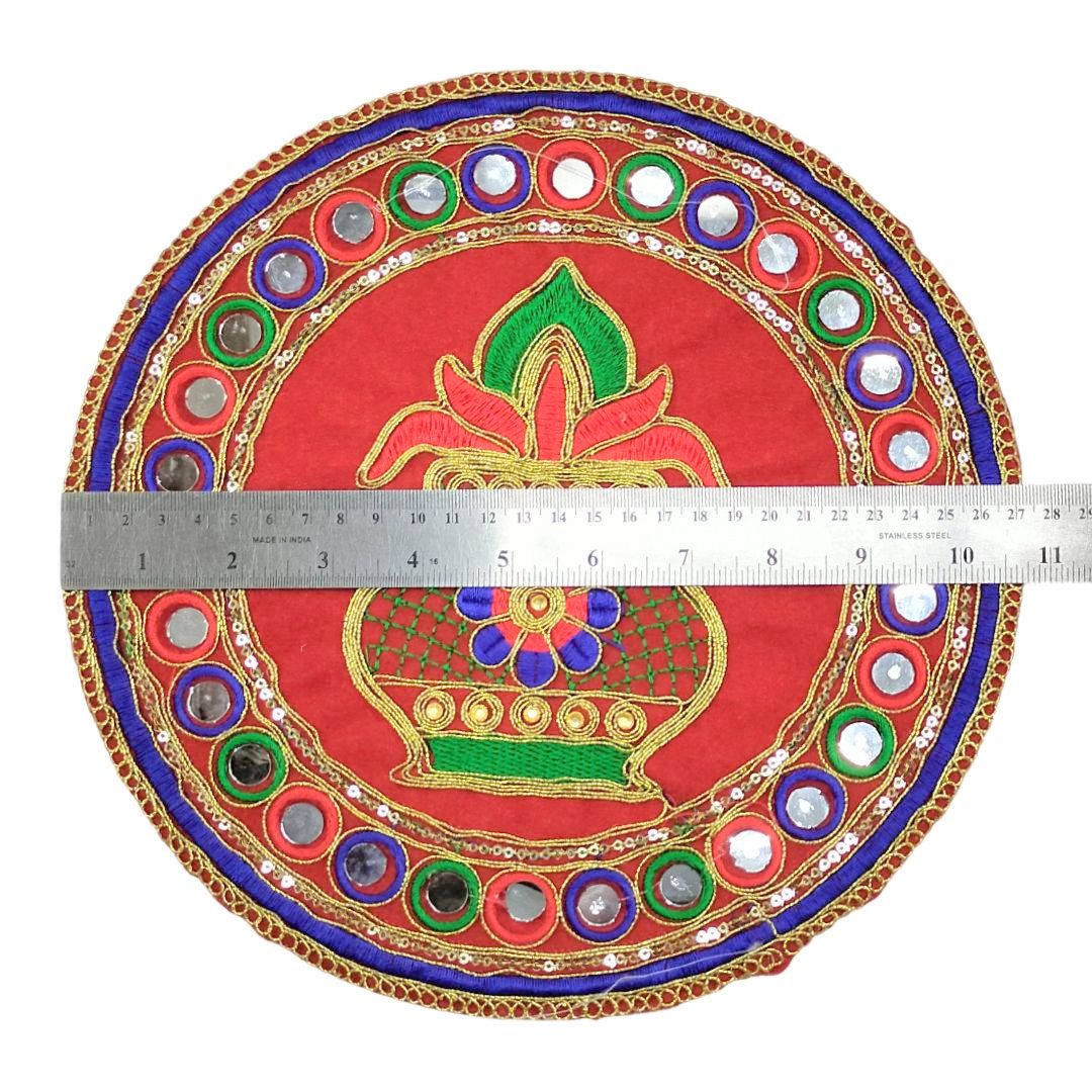 Decorative circular plate with intricate designs and a ruler for scale on a white background