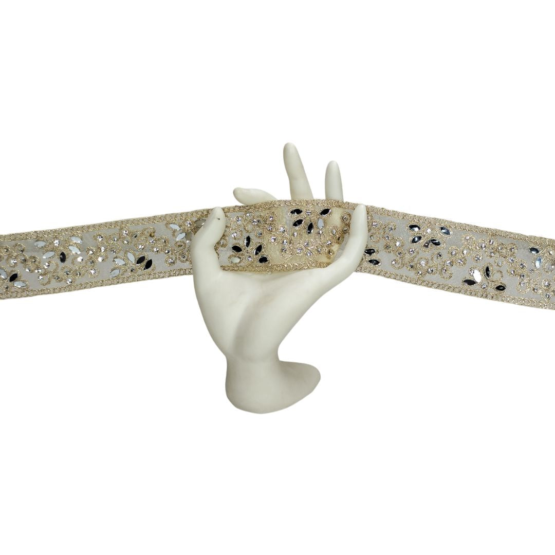 Decorative belt with glittery pattern and a white hand holding it on a white background