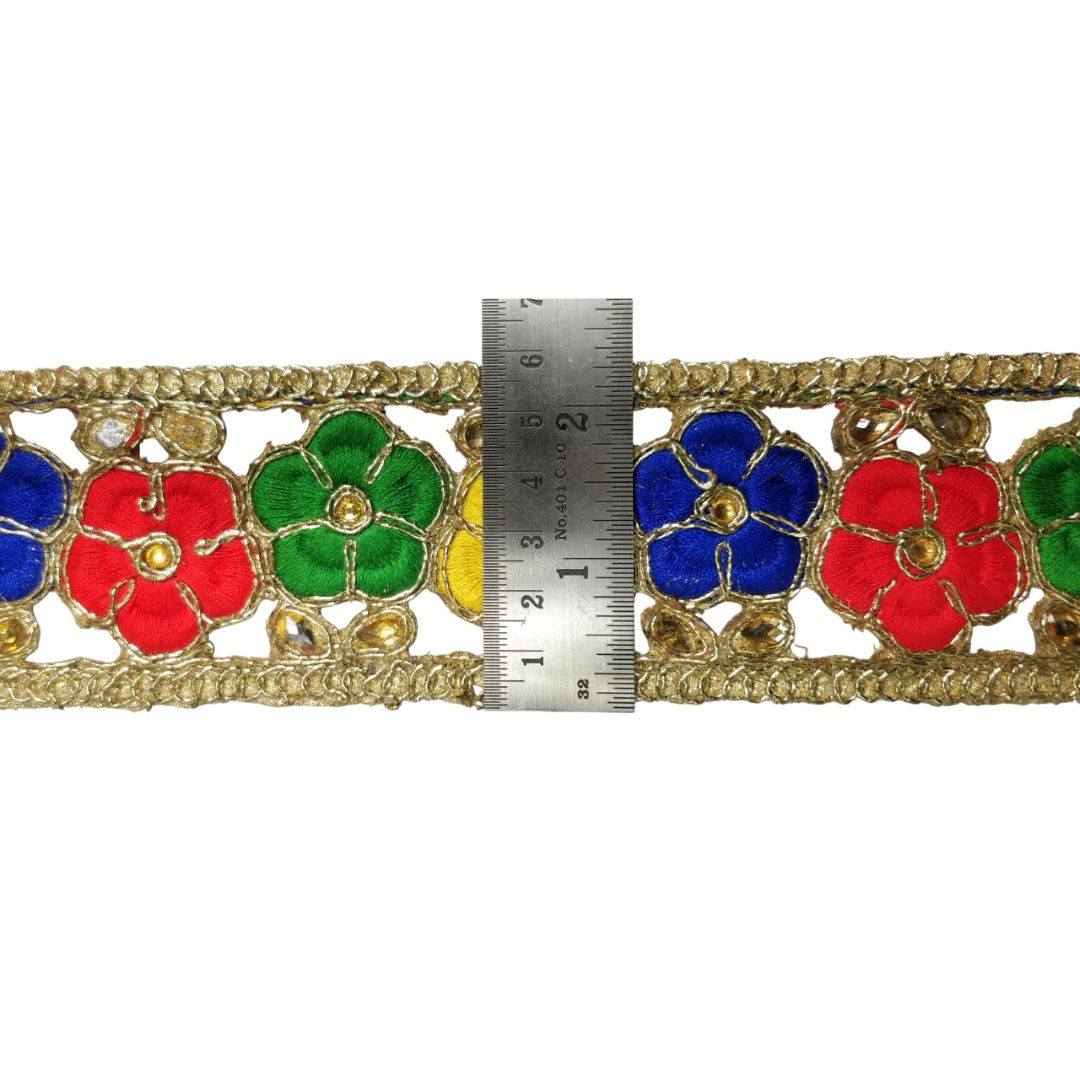 Decorative fabric trim with colorful flowers and a ruler for scale on a white background
