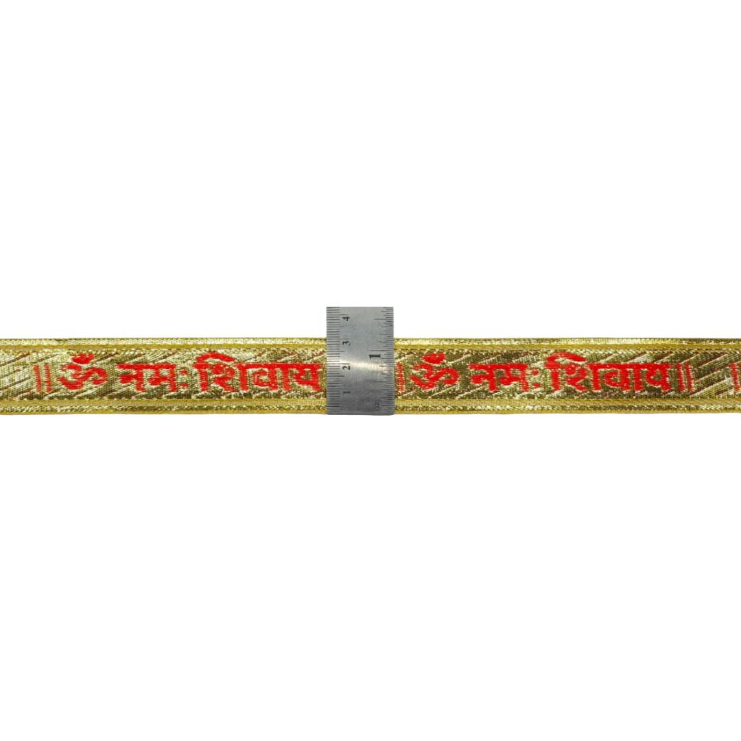 Gold thread with red text and a ruler for scale on a white background