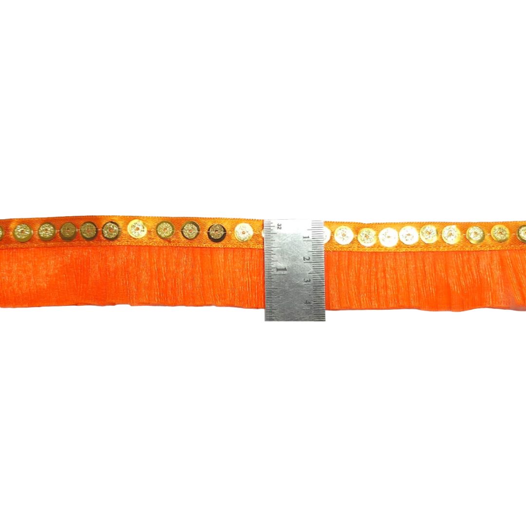 Orange belt with gold studs and a ruler for size reference on a white background
