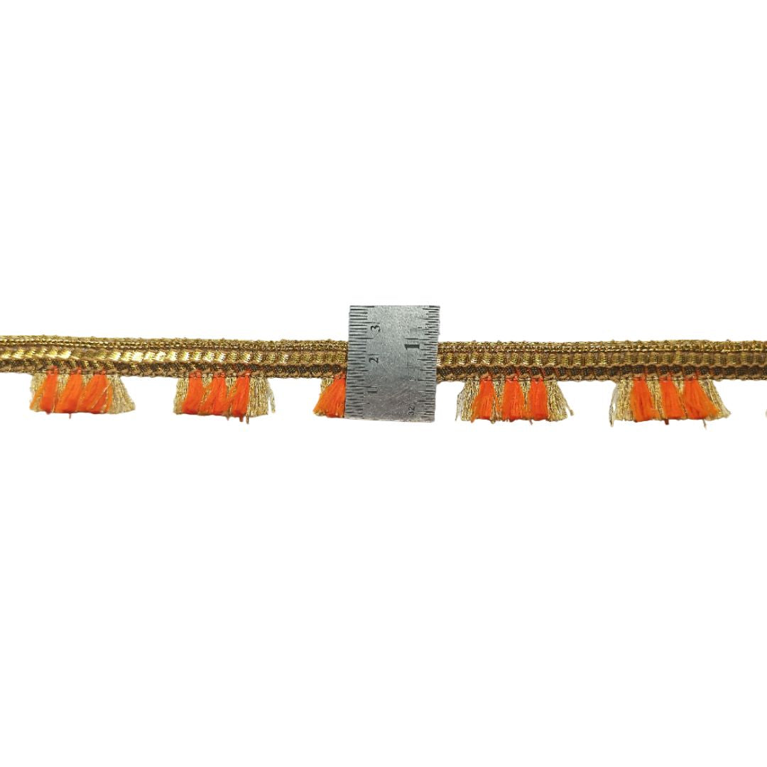 Decorative trim with orange tassels and a ruler for scale on a white background