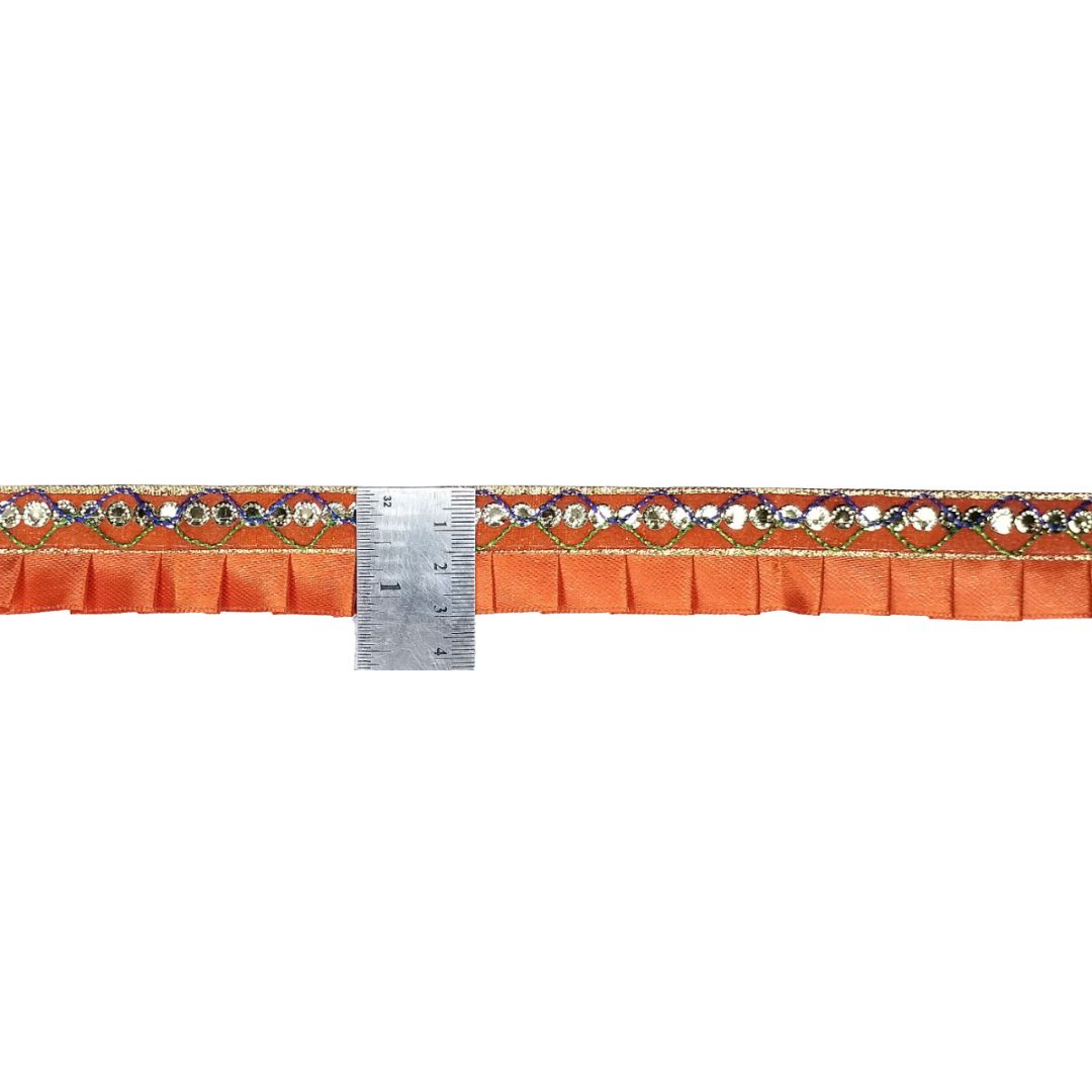 Orange fabric with decorative border and a ruler for measurement on a white background