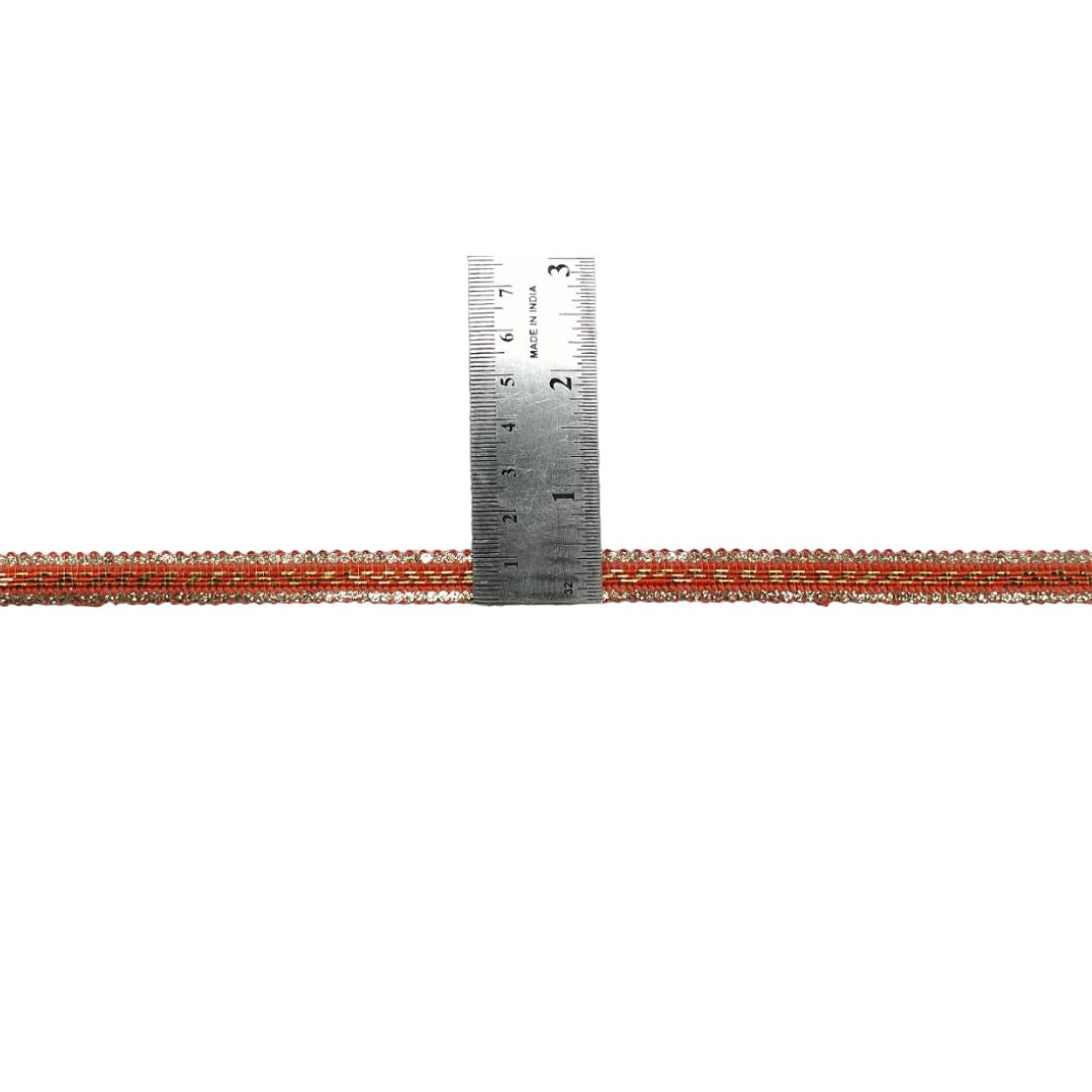 Metallic red and silver tube with a ruler for scale on a white background