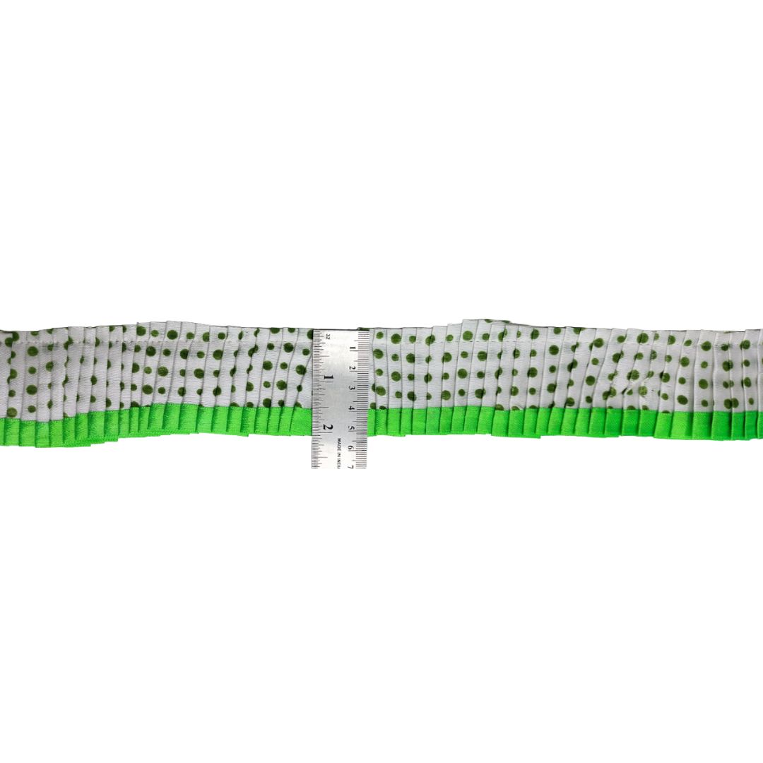 Green and white polka dot ribbon with a ruler for scale on a white background