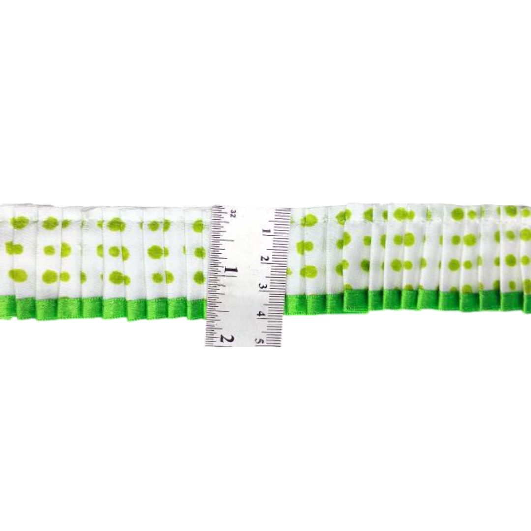 Green and white polka dot ribbon with a ruler for scale on a white background
