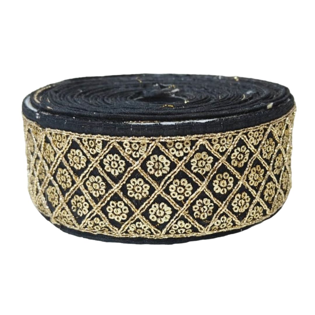 Roll of black ribbon with gold geometric pattern on a white background