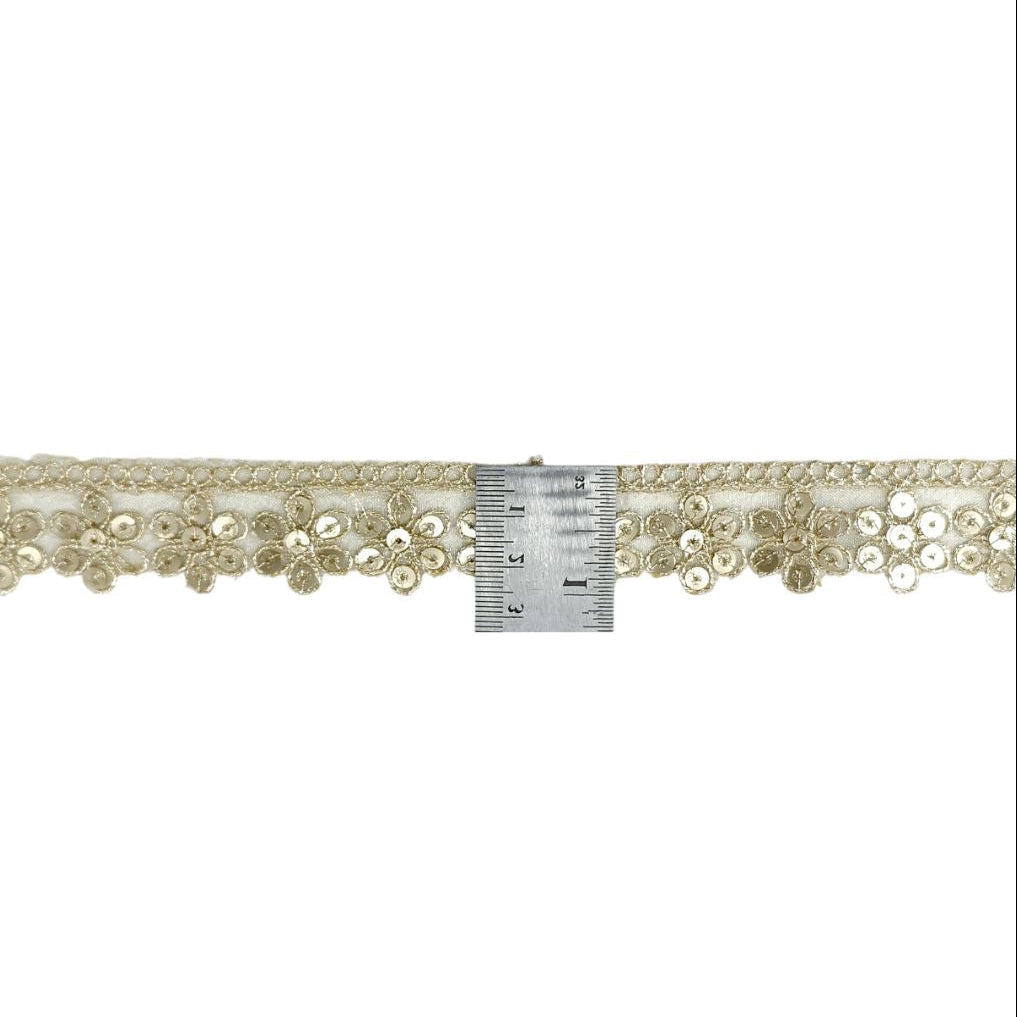 Decorative ribbon with beads and a measuring tape for scale on a white background