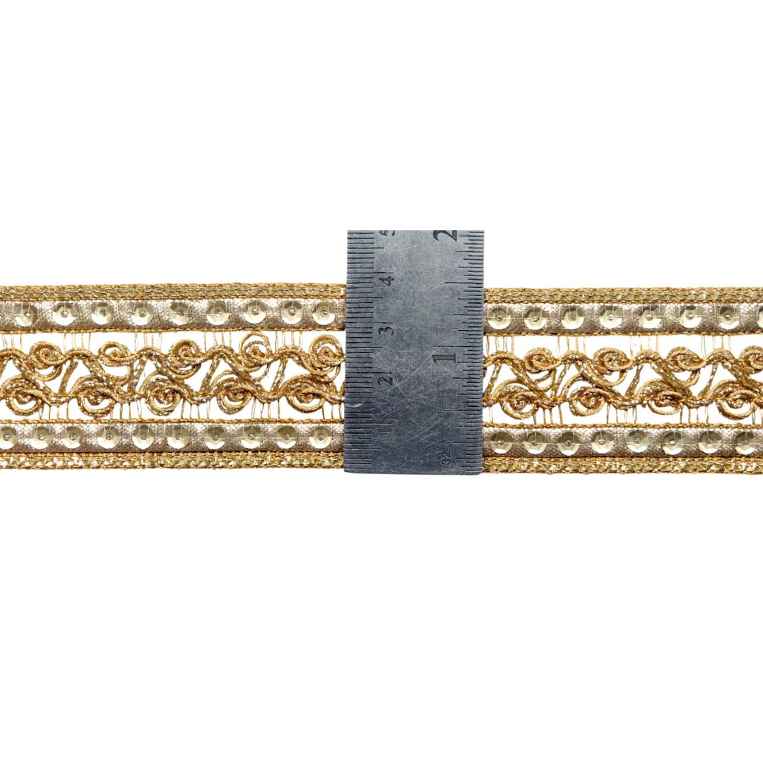 Decorative gold lace trim with a ruler for scale on a white background