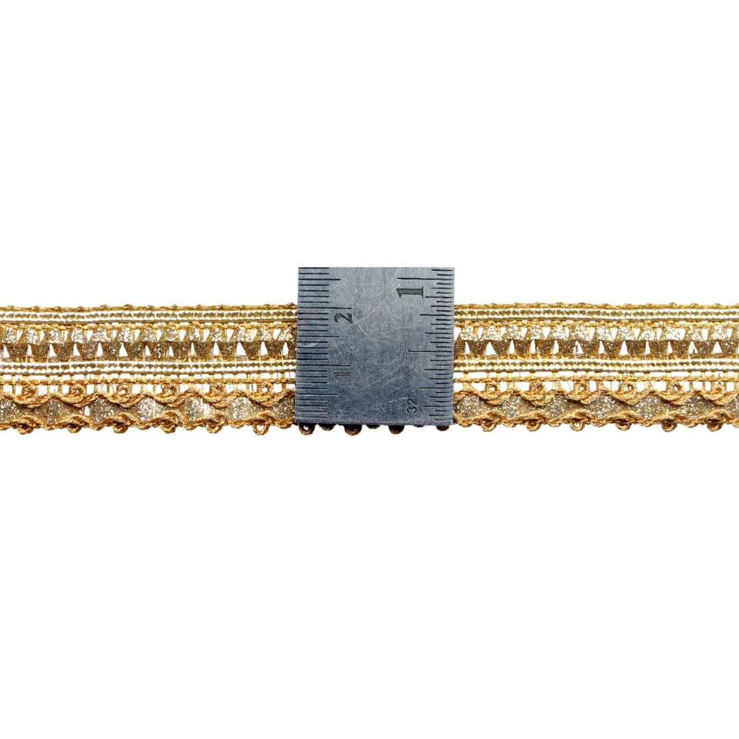 Gold jewelry with a ruler for scale on a white background