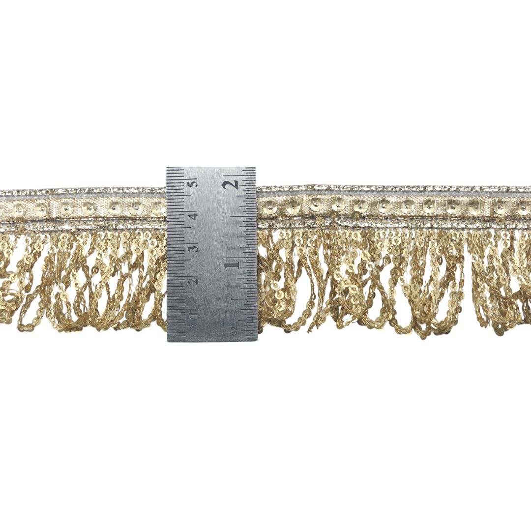 Gold fringe trim with a ruler for scale on a white background