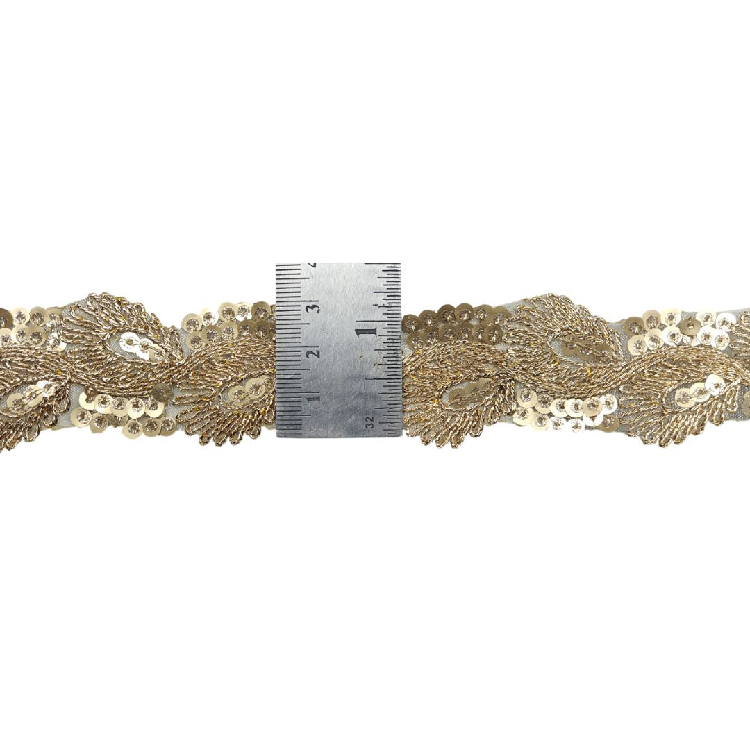 Gold lace trim with a ruler for scale on a white background