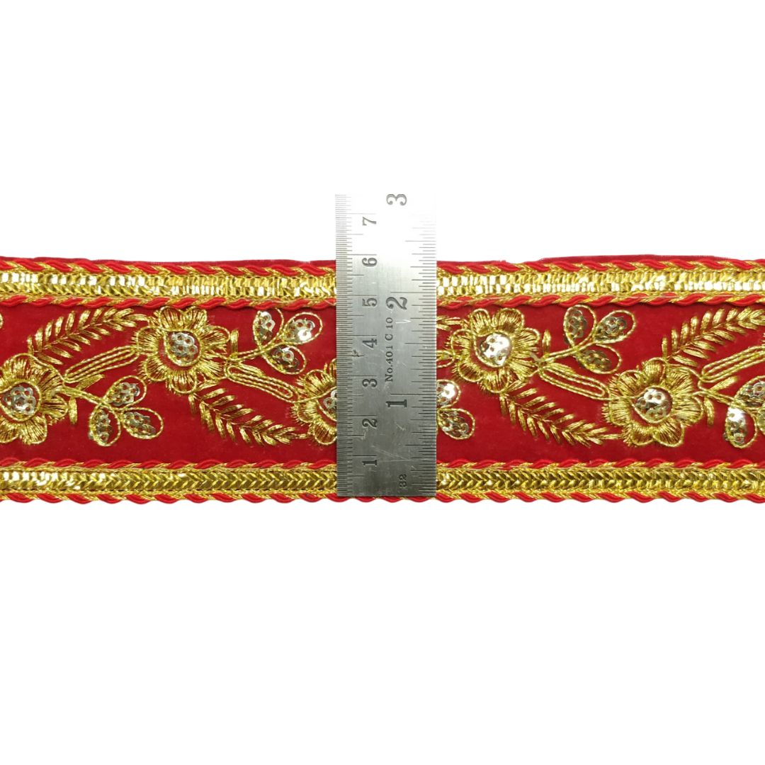 Decorative red ribbon with gold embroidery and a ruler for scale on a white background