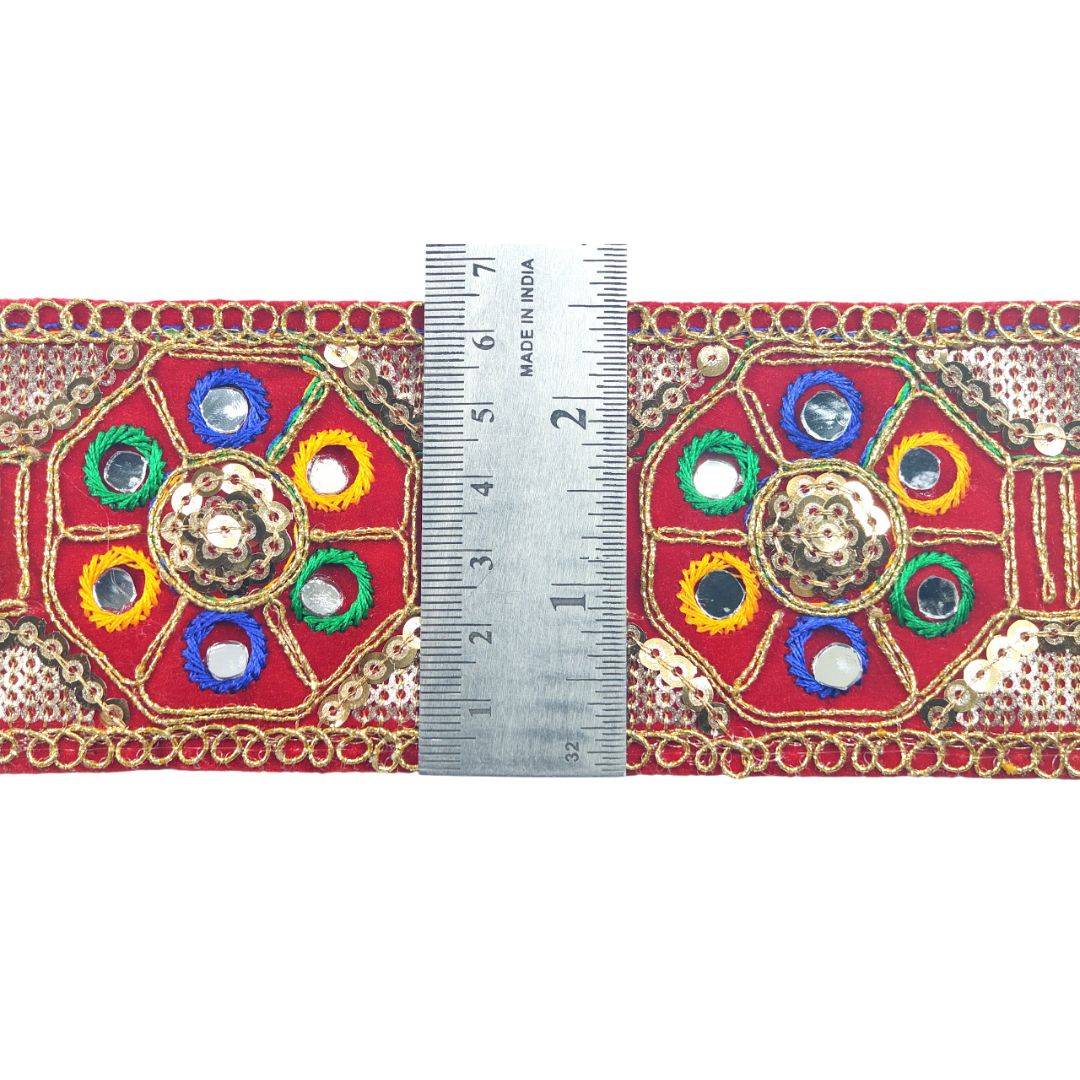 Decorative fabric border with colorful patterns and a ruler for scale on a white background