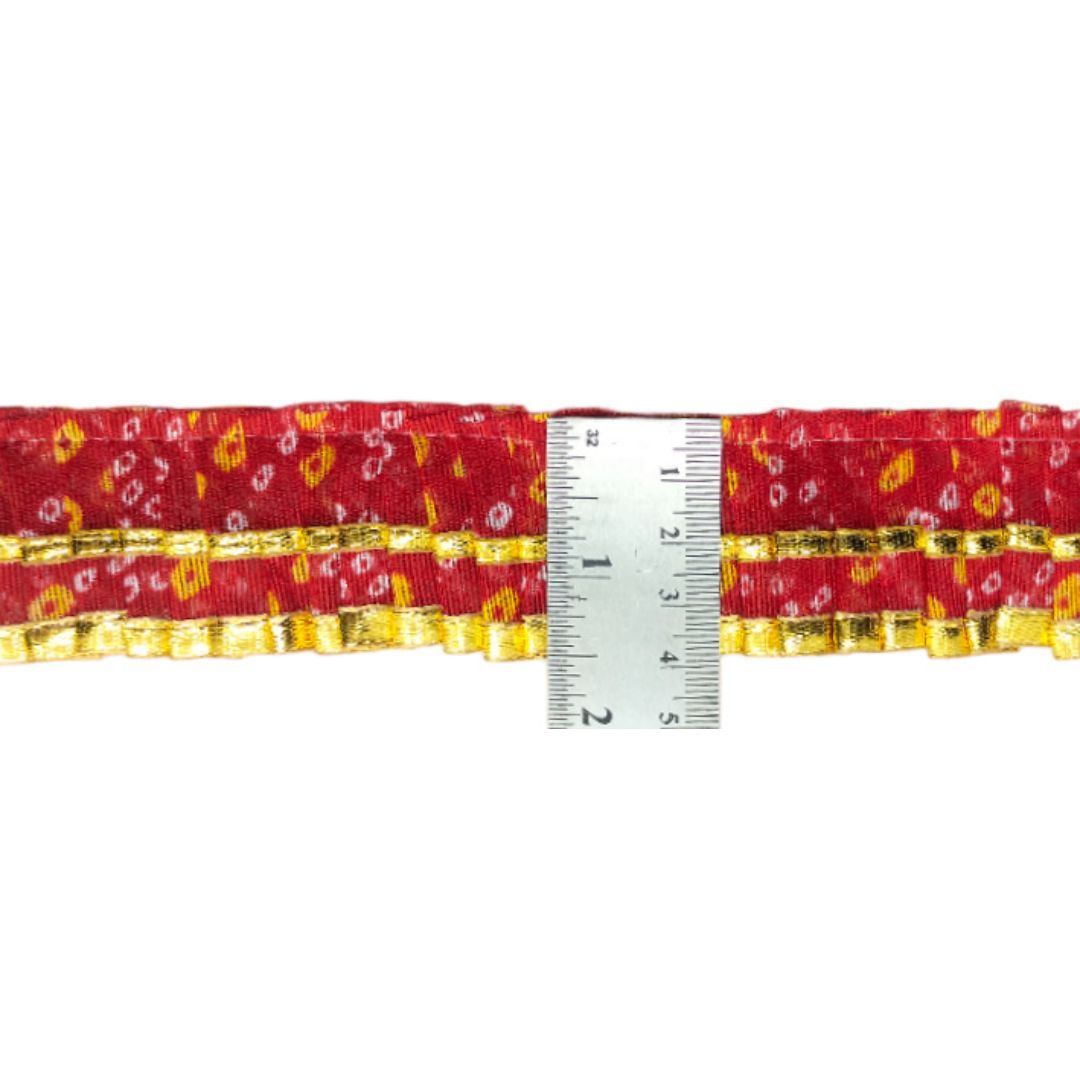 Red belt with gold patterns and a ruler for size reference on a white background