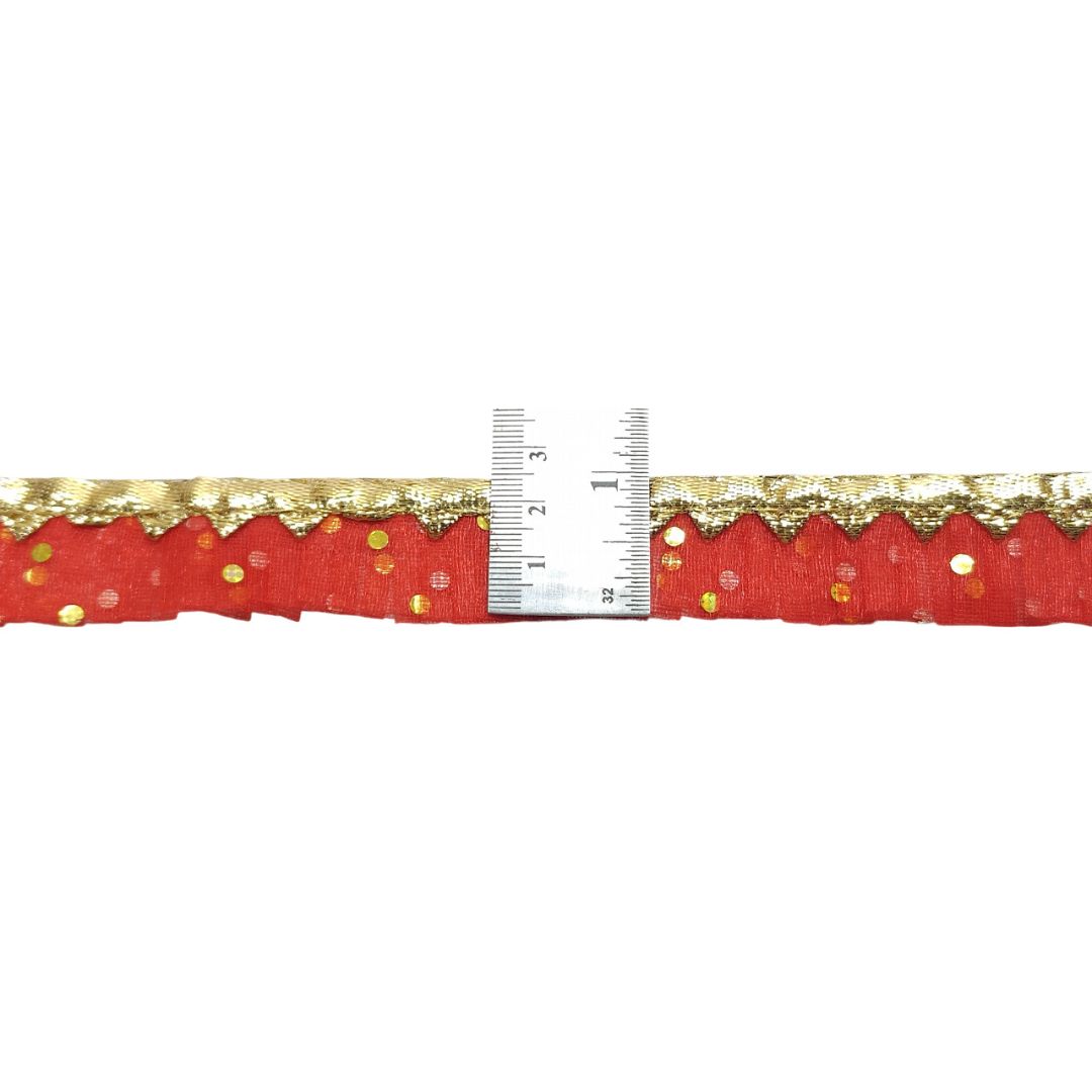 Red fabric with gold trim and a ruler for measurement on a white background