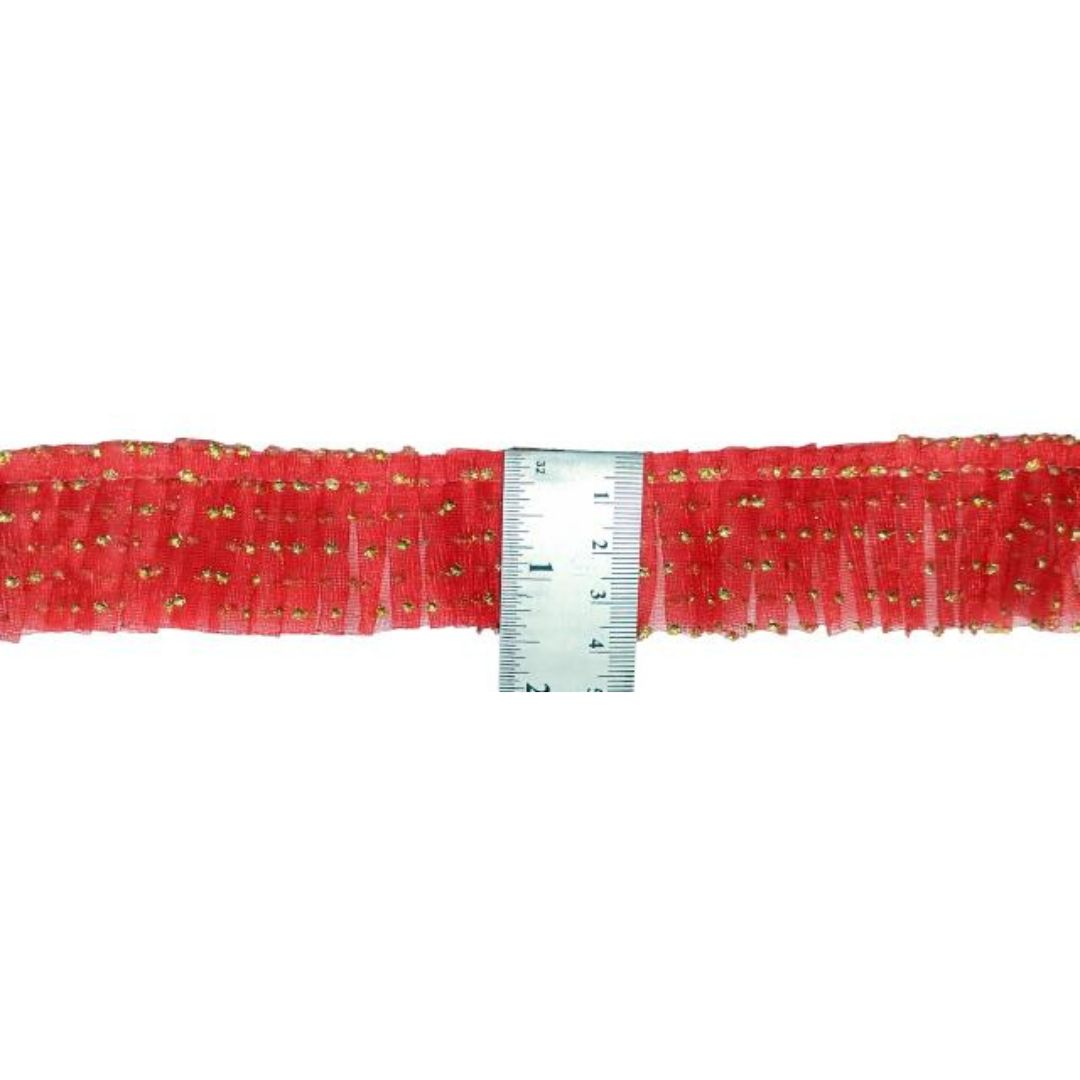 Red ribbon with gold sequins and a ruler for scale on a white background